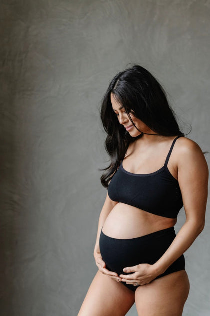 Shot Of A Beautiful Pregnant Woman Wearing Underwear And Holding